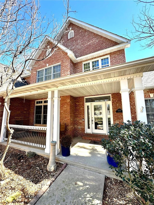 view of exterior entry with covered porch and brick siding