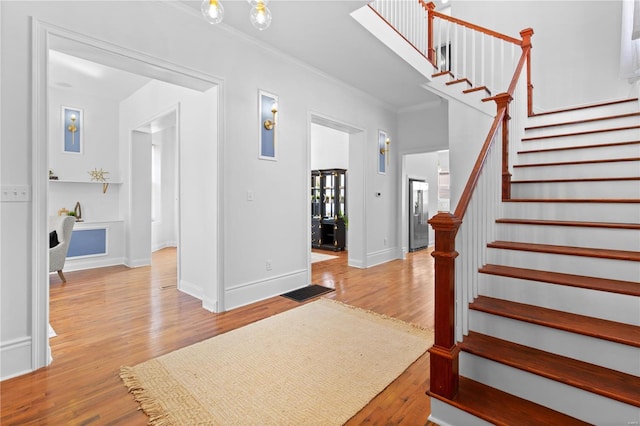 foyer featuring ornamental molding, stairway, baseboards, and wood finished floors