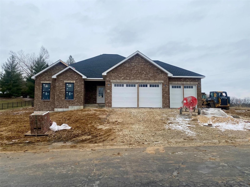 view of front of house with a garage, brick siding, and roof with shingles