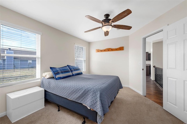 bedroom featuring carpet, multiple windows, baseboards, and a ceiling fan