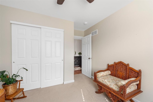 sitting room featuring baseboards, ceiling fan, visible vents, and light colored carpet