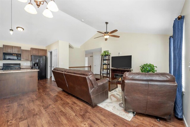 living area featuring lofted ceiling, dark wood-style floors, and ceiling fan with notable chandelier