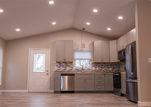 kitchen with hanging light fixtures, appliances with stainless steel finishes, vaulted ceiling, and gray cabinetry