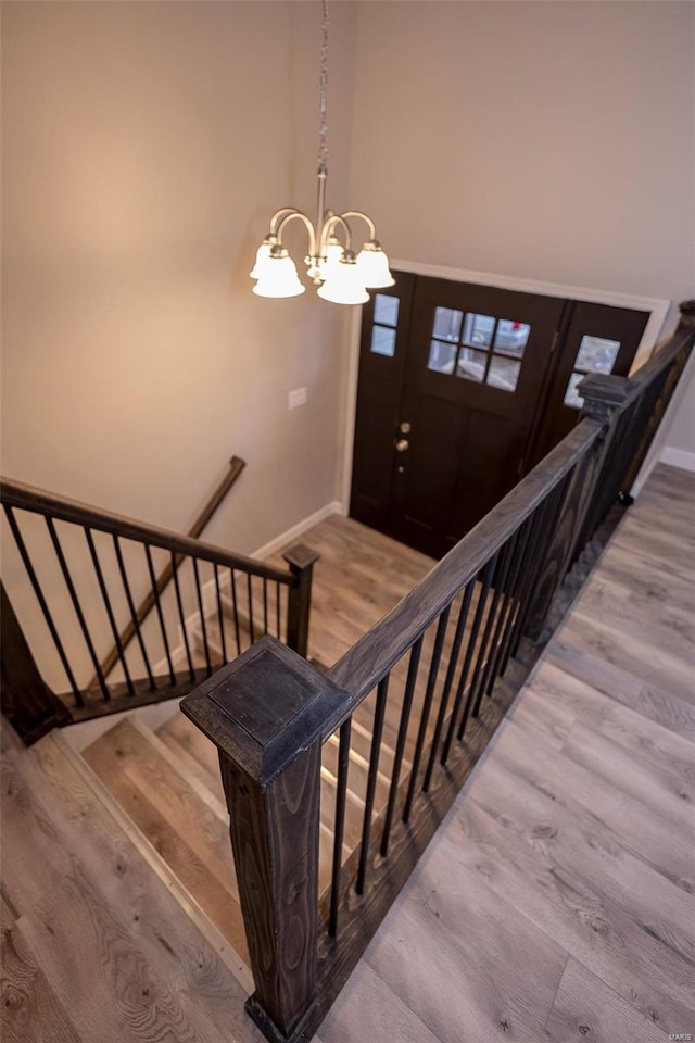 stairs with a notable chandelier, baseboards, and wood finished floors