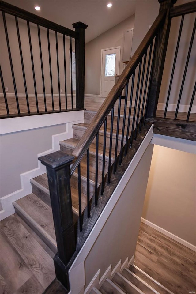 staircase featuring vaulted ceiling, baseboards, wood finished floors, and recessed lighting