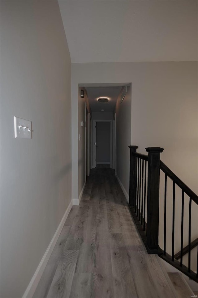 hall featuring wood finished floors, an upstairs landing, and baseboards