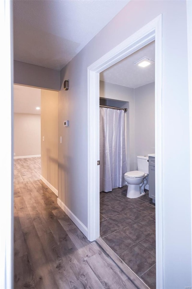 full bath with baseboards, toilet, and wood finished floors