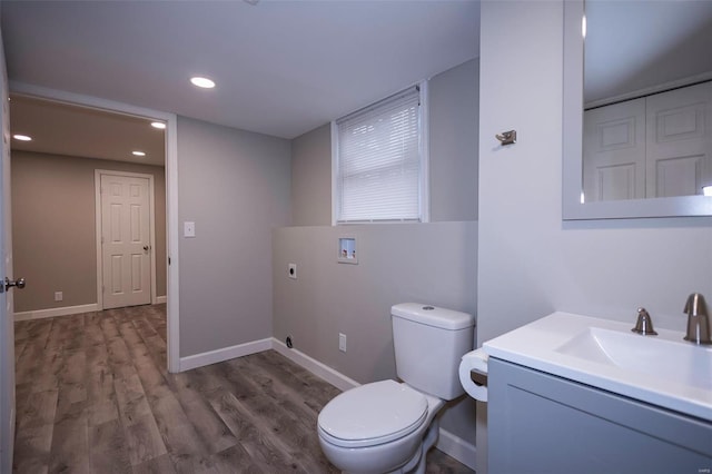 bathroom featuring toilet, baseboards, wood finished floors, and vanity