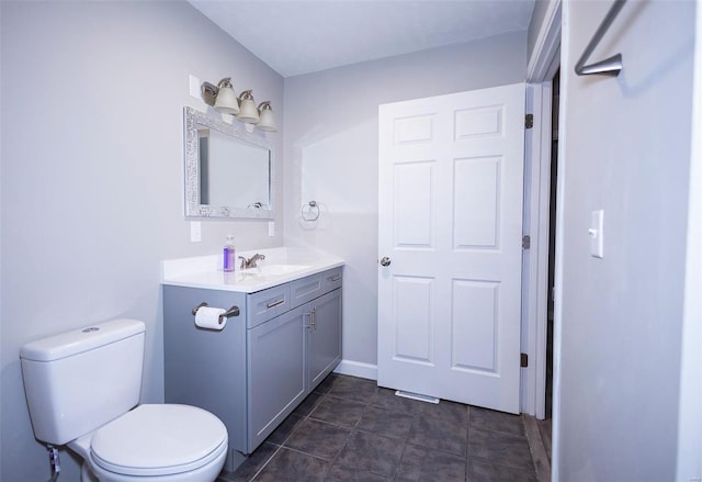 half bathroom featuring baseboards, vanity, toilet, and tile patterned floors