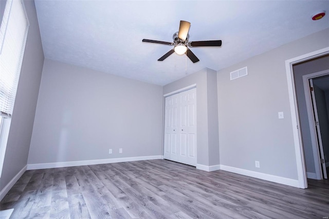 unfurnished bedroom featuring a closet, wood finished floors, visible vents, and baseboards