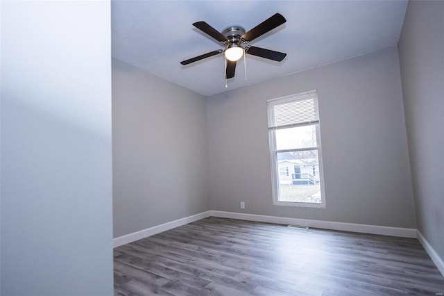 spare room featuring ceiling fan, wood finished floors, visible vents, and baseboards