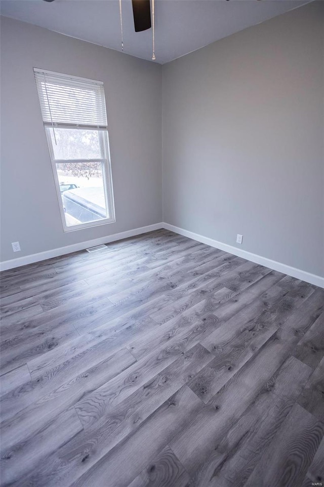 spare room featuring baseboards, visible vents, and wood finished floors