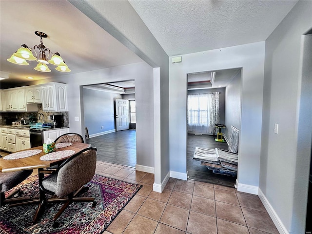 dining room with light tile patterned floors, a textured ceiling, baseboards, and an inviting chandelier