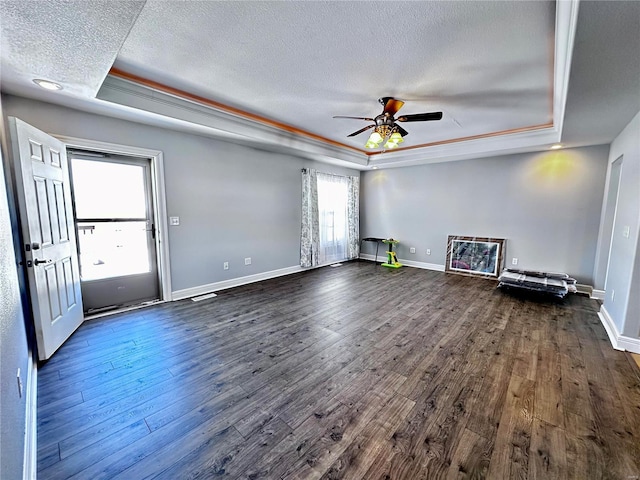 unfurnished living room with dark wood-style floors, baseboards, a tray ceiling, and a textured ceiling