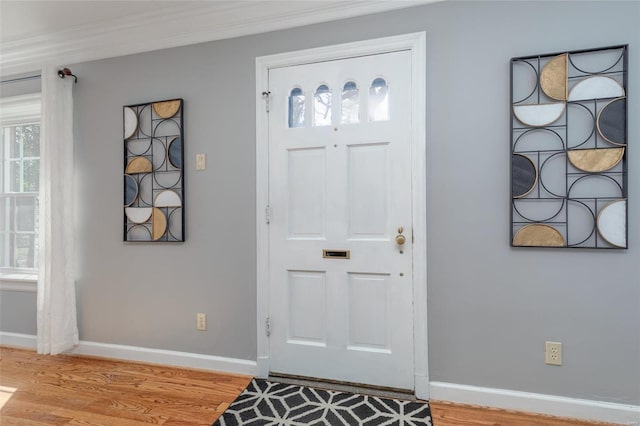 foyer with light wood-type flooring, baseboards, and ornamental molding