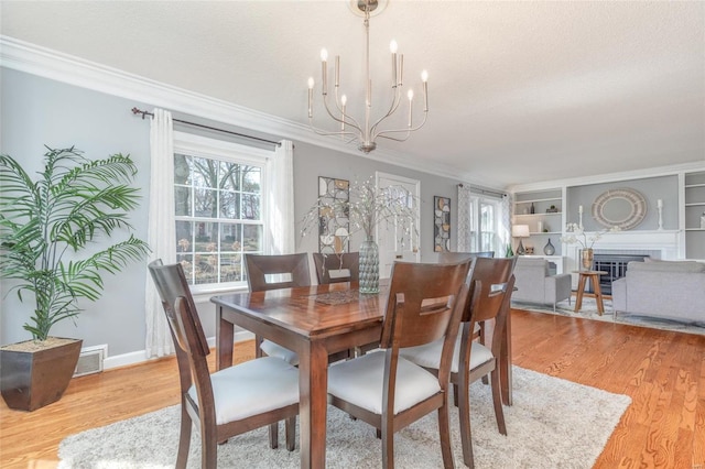 dining area featuring a chandelier, visible vents, light wood finished floors, and crown molding