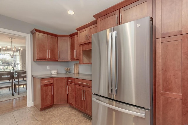 kitchen featuring a chandelier, light countertops, light tile patterned floors, brown cabinets, and freestanding refrigerator