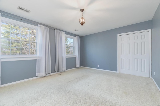 unfurnished bedroom featuring visible vents, baseboards, carpet, an inviting chandelier, and a closet