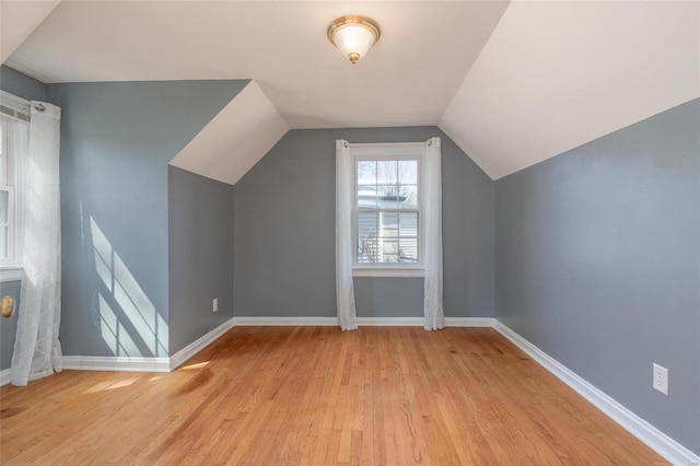 bonus room with baseboards, light wood-style floors, and lofted ceiling