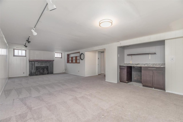 unfurnished living room with light carpet, a brick fireplace, wet bar, and rail lighting