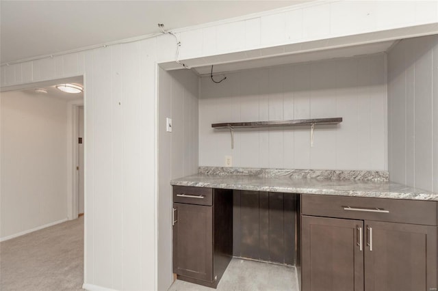 interior space featuring light carpet, dark brown cabinets, and light stone countertops