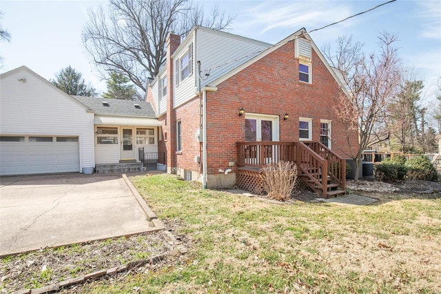 back of house featuring a yard, concrete driveway, an attached garage, brick siding, and a chimney