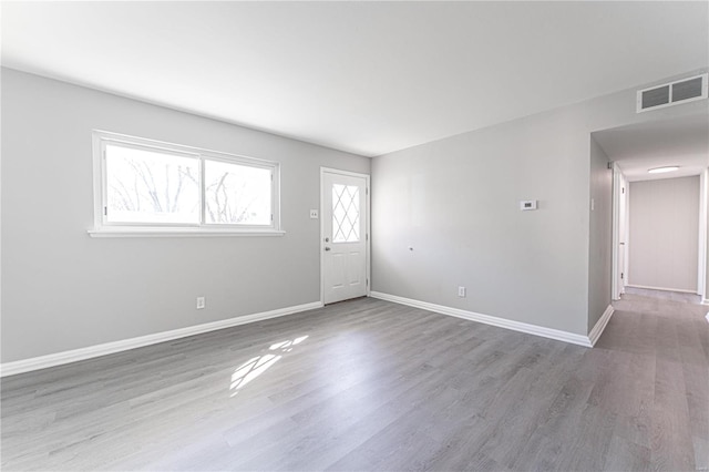 spare room featuring visible vents, baseboards, and wood finished floors