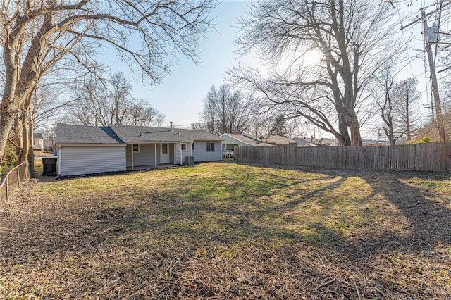 rear view of property featuring a yard and a fenced backyard