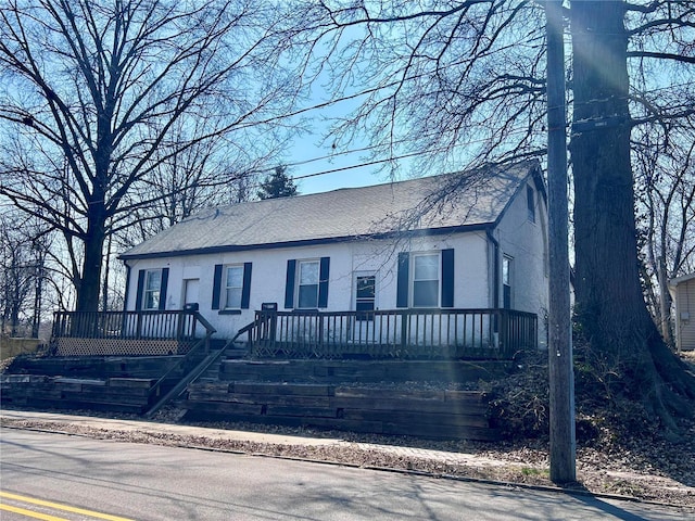 view of front of home featuring stucco siding and roof with shingles