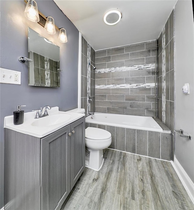 full bathroom with toilet, vanity, tiled shower / bath, and wood finished floors