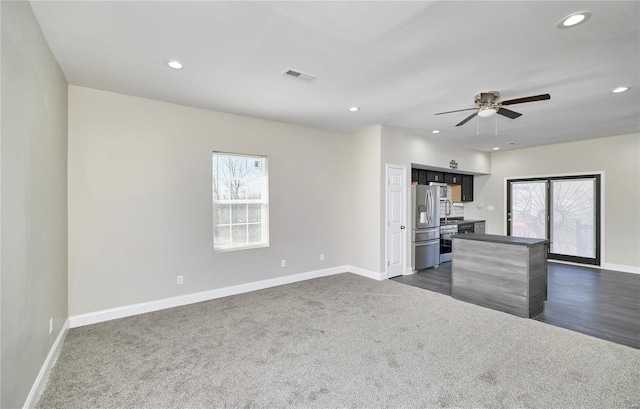 unfurnished living room with visible vents, baseboards, recessed lighting, ceiling fan, and dark colored carpet