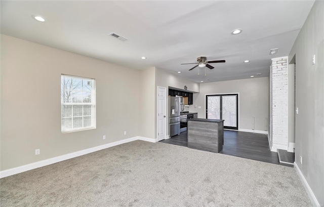 unfurnished living room featuring a wealth of natural light, visible vents, recessed lighting, and dark carpet