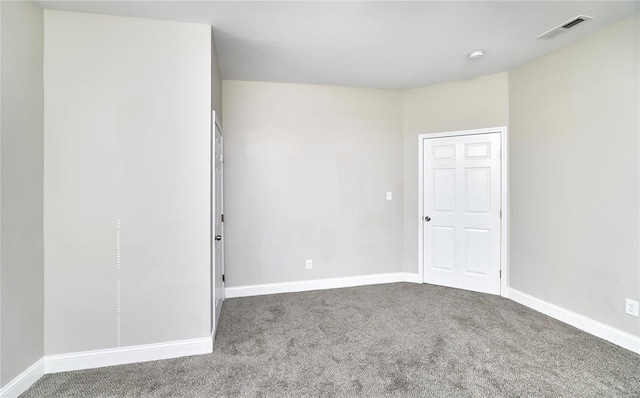 empty room with carpet, visible vents, and baseboards