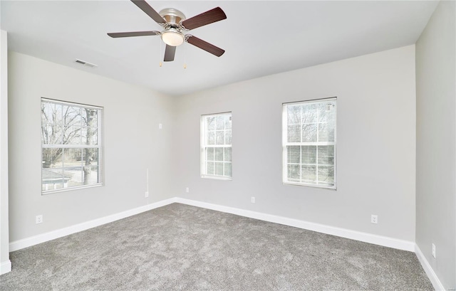 carpeted spare room with visible vents, baseboards, and ceiling fan