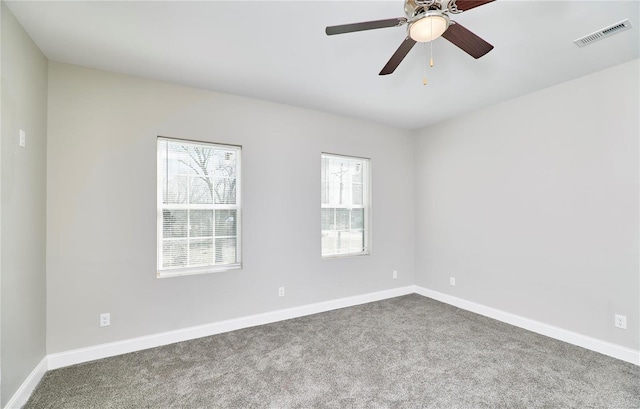 carpeted spare room featuring visible vents, baseboards, and ceiling fan