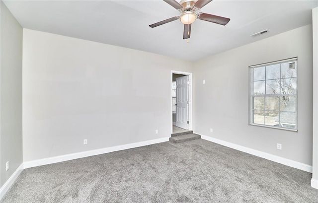 carpeted empty room with visible vents, a ceiling fan, and baseboards