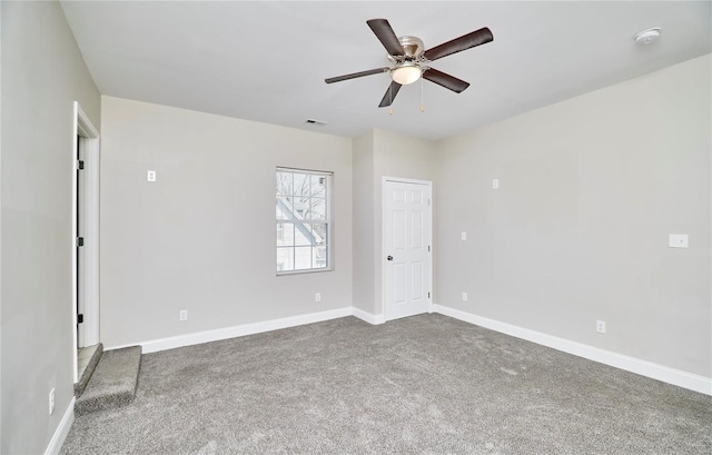 carpeted empty room featuring a ceiling fan, visible vents, and baseboards