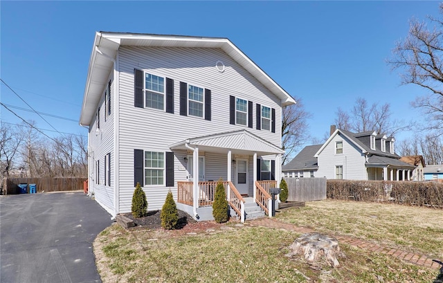 view of front facade featuring a front yard, fence, covered porch, and driveway