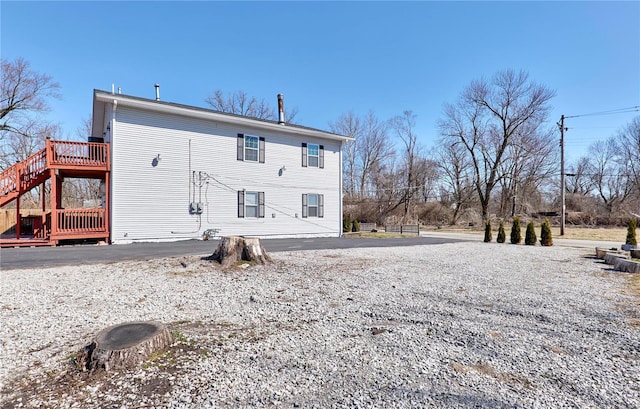 rear view of property featuring a wooden deck and stairs