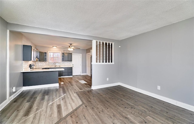 kitchen featuring baseboards, a peninsula, dark wood-type flooring, light countertops, and tasteful backsplash