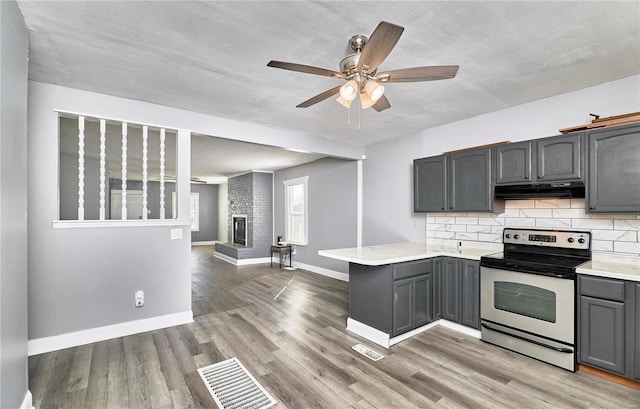 kitchen featuring light wood-type flooring, gray cabinets, under cabinet range hood, stainless steel range with electric cooktop, and a peninsula