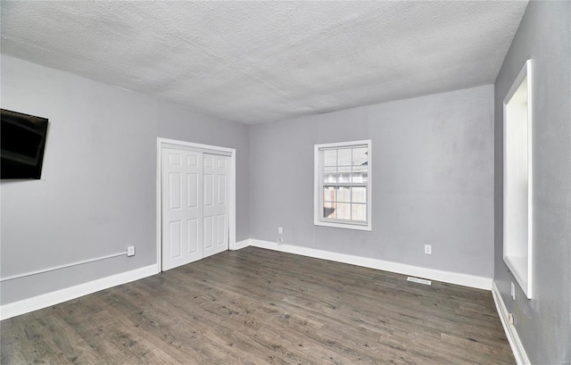 interior space featuring baseboards, dark wood-style flooring, a closet, and a textured ceiling