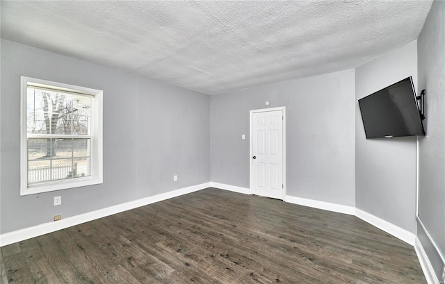 empty room with dark wood-style floors, a textured ceiling, and baseboards