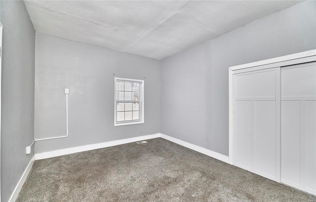 empty room with visible vents, a textured ceiling, baseboards, and carpet floors