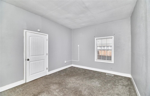 spare room featuring baseboards, visible vents, carpet floors, and a textured ceiling