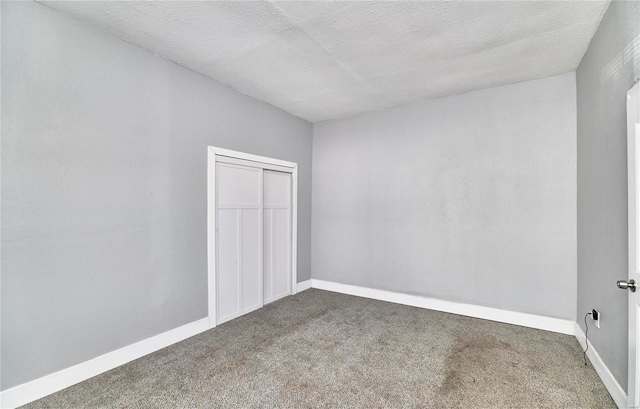 carpeted spare room with baseboards and a textured ceiling