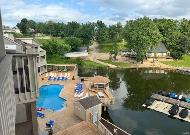 pool featuring a deck with water view, an outdoor structure, and a storage shed