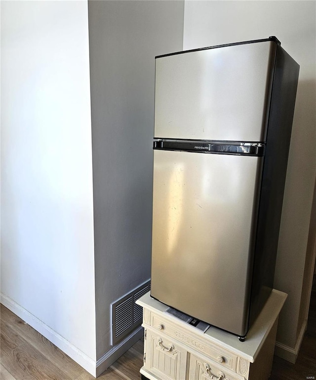 details with visible vents, wood finished floors, and freestanding refrigerator