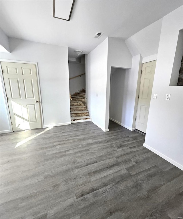 unfurnished room featuring baseboards, visible vents, stairs, and wood finished floors