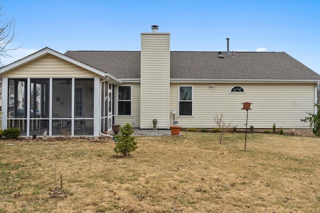 back of house featuring a sunroom, roof with shingles, a chimney, and a yard